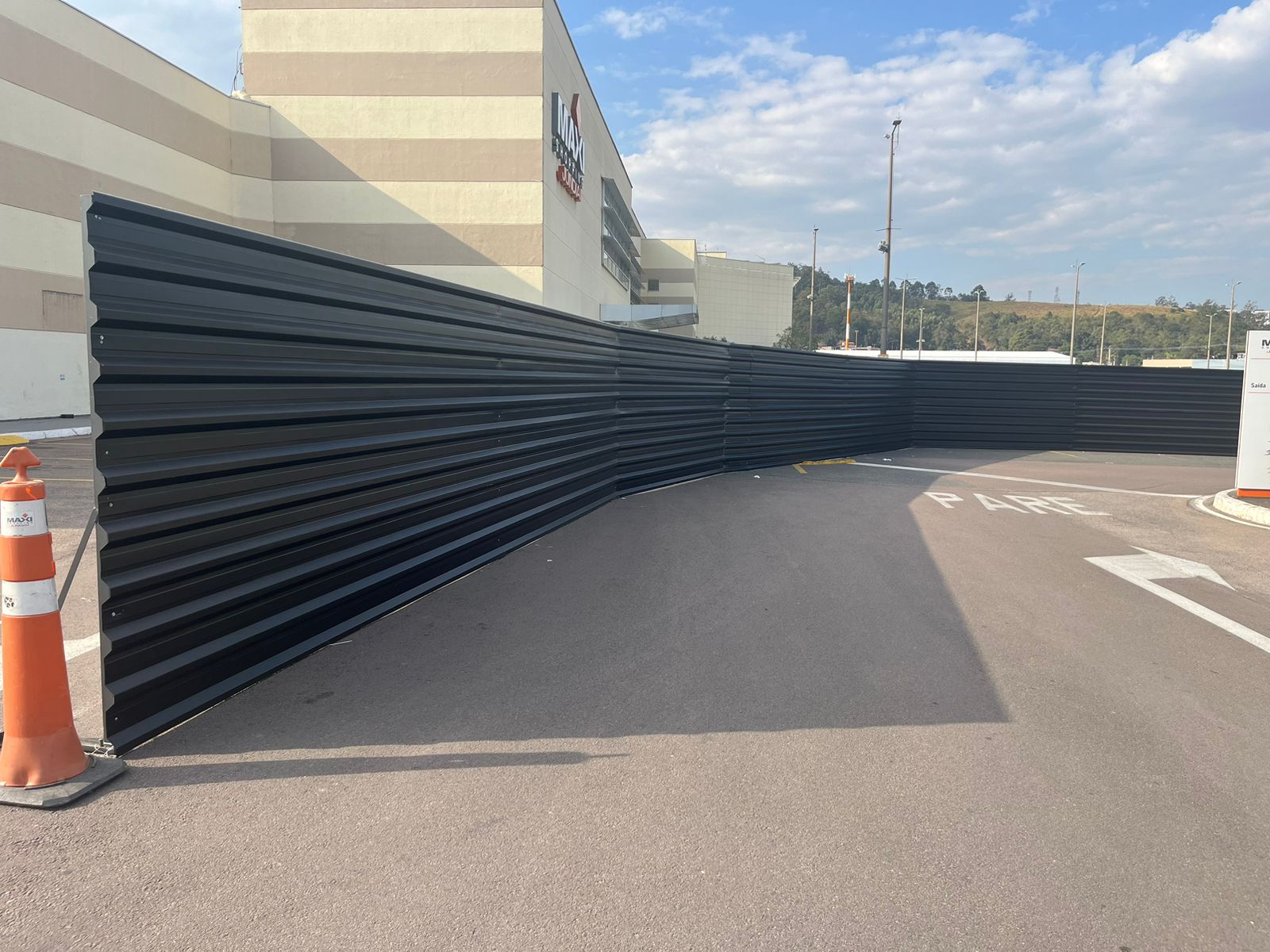 Tapume externo metálico preto com encontro em ângulo em área de circulação comercial